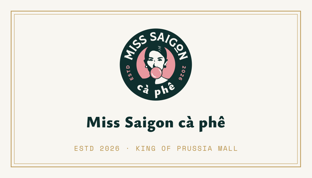 Card B front: cream card with brass frame, the badge and the Miss Saigon cà phê wordmark